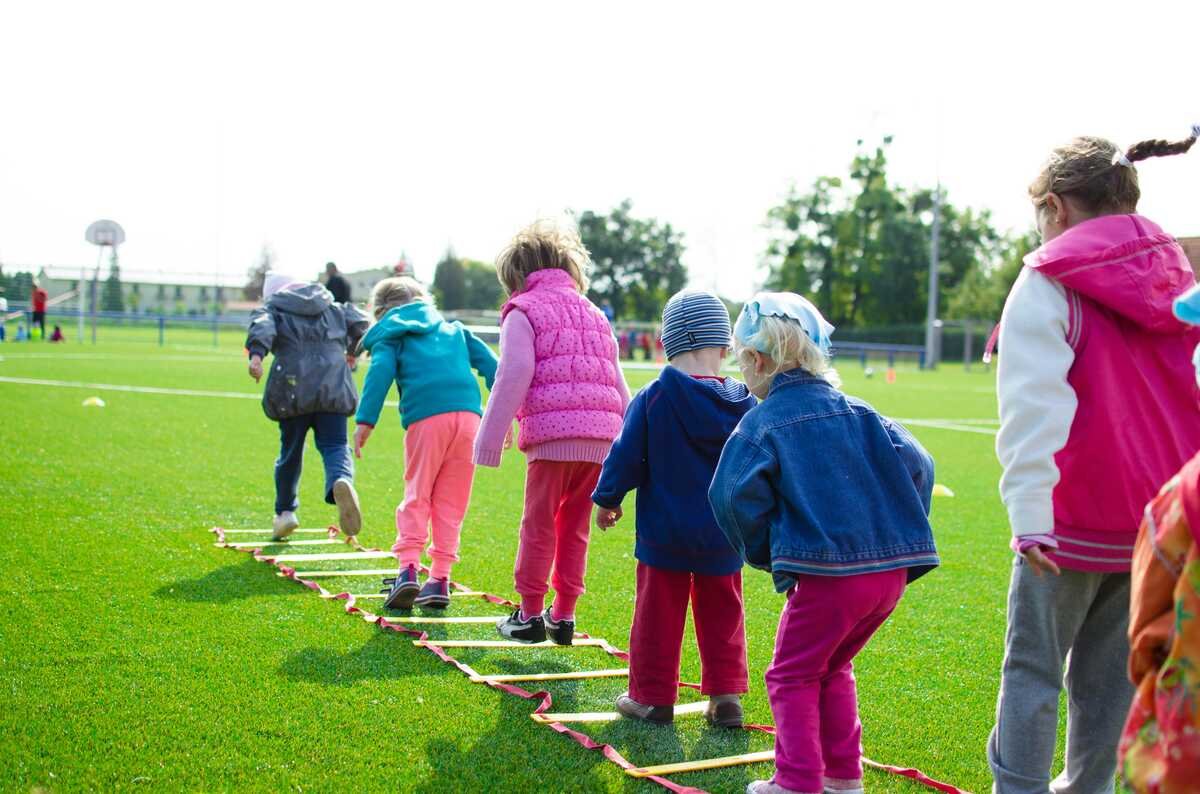 Group of young children playing outdoors on a green field