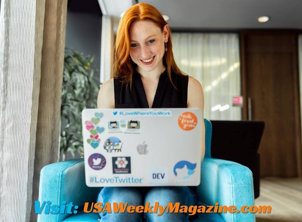 Young woman smiling while working on a laptop with stickers, exploring Beverly Hills Los Angeles zip code